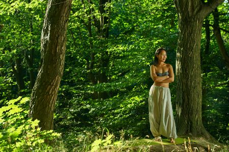 Young asian woman resting after yoga in the forest Beautiful portrait of yoga. Outdoors lifestyle portrait. Vacation, summer, relaxation. Harmony with nature.の写真素材