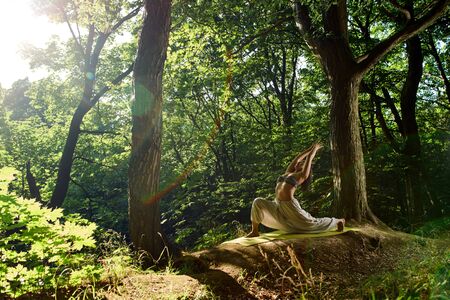 Young sporty attractive asian woman practicing yoga outdoors doing Warrior exercise Virabhadrasana pose. Outdoors lifestyle portrait. Beautiful portrait of yoga for lifestyle design.の写真素材