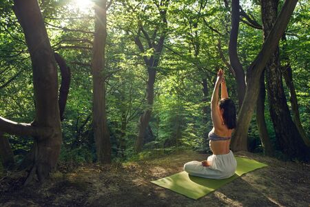 Yoga outdoor. Woman doing yoga exercises meditation in nature. Concept of healthy lifestyle relaxation. Woman practicing yoga on the park. Body relaxation. Asana yoga pose. Harmony with nature.の写真素材