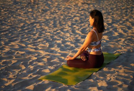 Woman meditates while practicing yoga by the sea at dawn Freedom concept Calmness and relax, woman happiness. Body relaxation. Asana yoga pose. Beautiful portrait of yoga. Outdoors lifestyle portrait.の写真素材
