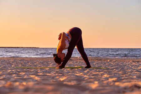 Young woman doing variation of Trikonasana yoga pose Practicing yoga in the nature at sunset. Female happiness. Healthy fitness background. Asana yoga pose. Vacation, summer. Healthy lifestyle.の写真素材