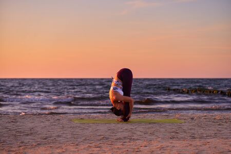 Asian woman practicing yoga, standing from head to knee exercises, Uttanasana pose, working out, wearing sportswear, side view Spiritual Travel Relaxation Lifestyle Concept. Harmony with natureの写真素材