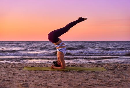Girl doing yoga exercise shirshasana The concept of a healthy lifestyle and a natural balance between the body and mental development Whole length Asana yoga pose Beautiful portrait of yoga Back view.の写真素材