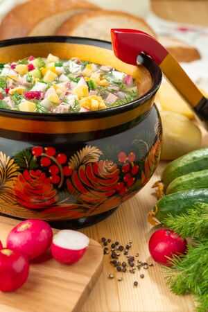 Traditional Russian summer cold okroshka soup with kefir in a bowl on a wood background. View from above. Khokhloma-style wooden dishes. Russian Khokhloma, traditional wood painting. ?lose ups photo.の写真素材