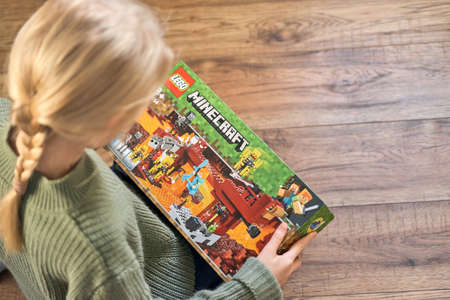 January 5, 2020, Kaliningrad, Russia. A little girl with blond hair is holding a new box of Lego Minecraft and looks at it.のeditorial素材