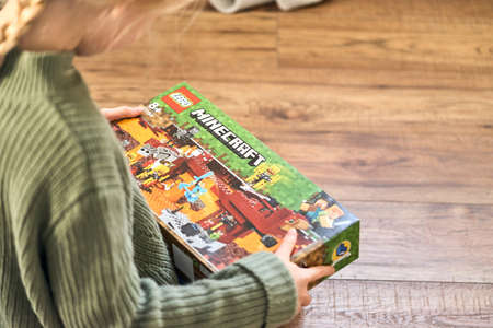 January 5, 2020, Kaliningrad, Russia. A little girl with blond hair is holding a new box of Lego Minecraft and looks at it.のeditorial素材