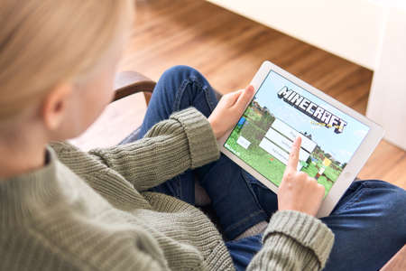 January 5, 2020, Kaliningrad, Russia. Little girl with blond hair start playing Minecraft game on Apple iPad Air. Minecraft is a very popular game among children and adolescents.のeditorial素材