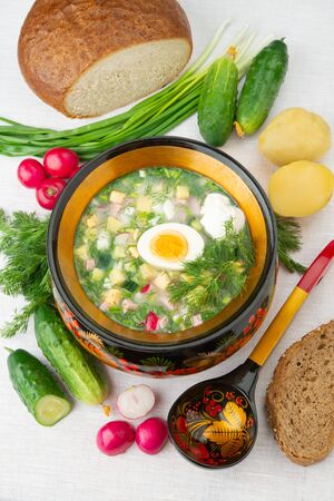 Traditional Russian summer cold okroshka soup with kefir in a bowl on a white background. View from above. Khokhloma-style wooden dishes. Russian Khokhloma, traditional wood painting.の写真素材
