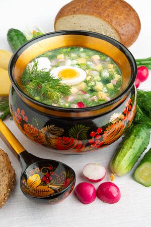 National Russian cuisine Okroshka summer cold yogurt soup in a wooden bowl. Radish, eggs, cucumber, green onions, dill. Top view. Russian Khokhloma, traditional wood painting. White background.の写真素材