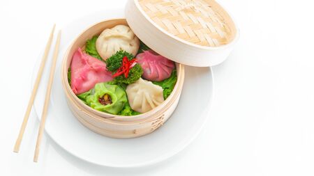 Multi-colored chinese steamed dumplings Dim Sums in bamboo steamer with chopsticks on light surface with copy space. Asian food restaurant background.の写真素材