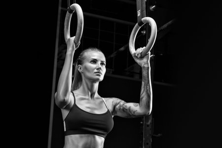 Close up of woman holding gymnastic rings at the gym and look into the distance. Fitness young woman...