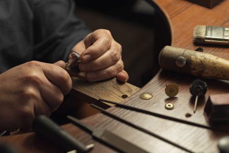 Master of jewelry manually polishing golden ring with diamonds. Working desk for craft jewelery...