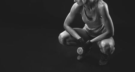 Horizontal black and white photo of fitness woman sitting on the floor Attractive slim girl in sportswear relaxing after training. Copy space on leftの写真素材