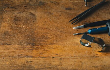 Jewelry craftsmanship. Handmade. Jeweler at work. The jeweller engraver tools on wooden vintage desk. Tweezers, Magnifier, Chisel Hand Engraving Top view Copy free spaceの写真素材