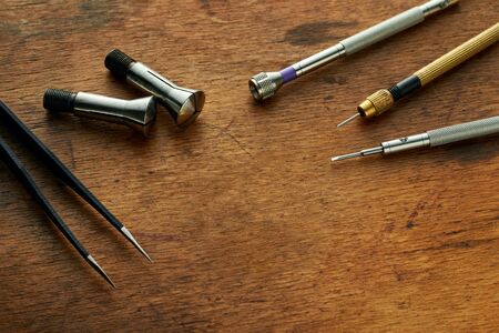 Various Tools On A Watchmakers Vintage Wooden Table. Closeup photo of wristwatch repair tools with copy space in the center Special tools for repair of clocks Template Mockup Concept backgroundの写真素材
