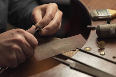 Working desk for craft jewelery making with professional tools. Master of jewelry manually polishing golden ring with diamonds. Diamond wedding ring on the jewelers desktopの写真素材