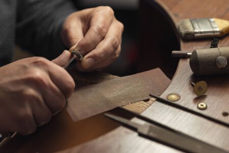 Working desk for craft jewelery making with professional tools. Master of jewelry manually polishing golden ring with diamonds. Diamond wedding ring on the jewelers desktopの素材 [FY310147331214]