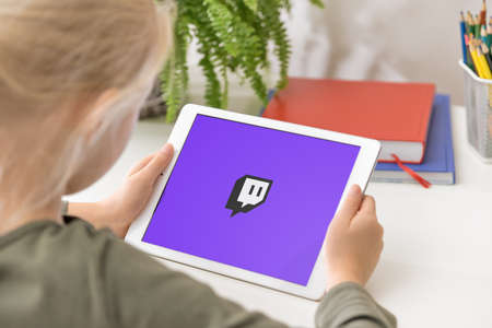 January 5, 2020, Kaliningrad, Russia. Twitch application start-up screen. Young girl holding iPad in her hands with Twitch application on the screen. Twitch is a video live streaming serviceのeditorial素材