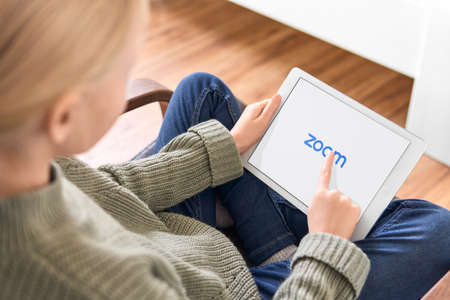 January 5, 2020, Kaliningrad, Russia. Little girl using Zoom mobile app to join a meeting from her iPad. iPad showing Zoom Cloud Meetings app logo. Homeschooling during quarantine coronavirus outbreakのeditorial素材