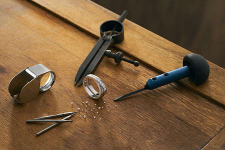 Workplace of a jeweler with tools and equipment for working on an old wooden table.の写真素材