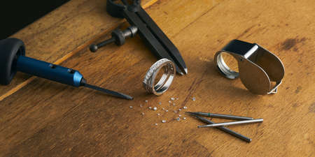 Tools and equipment for jewelry work on an antique wooden desktop.の写真素材