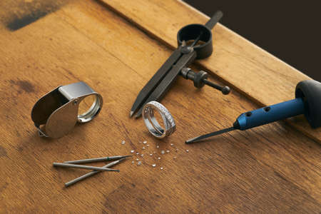 Tools and equipment for jewelry work on an antique wooden desktop.の写真素材