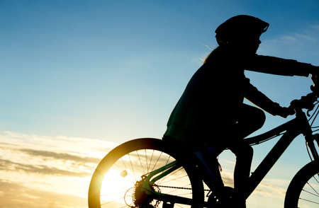 Girl is cycling road bike in the sunsetの写真素材