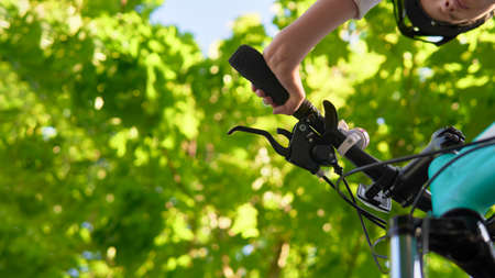 A teenager girl in a bicycle helmet rides a bicycle in the parkの写真素材