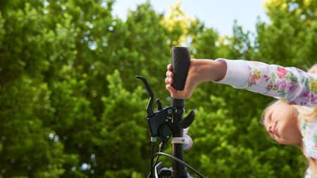 A teenager girl in a bicycle helmet rides a bicycle in the park.の写真素材