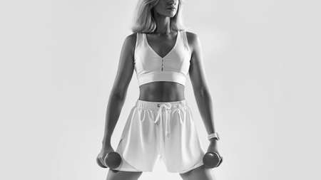 Smiling fitness woman standing with dumbbellの写真素材
