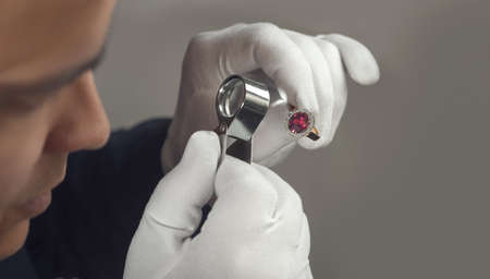 Goldsmith examining gold ruby ring in workshopの写真素材