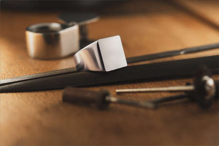 Signet ring on the wooden antique table with professional goldsmith toolsの写真素材