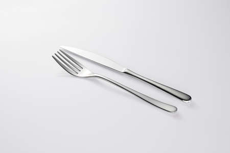 Stylish classy elegant metallic eating knife and fork cutlery for dining kitchen utensils Isolated on a white background, well lit. Kitchen set Flatware on white.の写真素材
