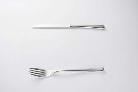 Knife and fork flat lay pattern on pastel pink background. Many metallic forks, and knives top view concept. Background for menu. Restaurant backdrop. Creative top view pattern.の写真素材