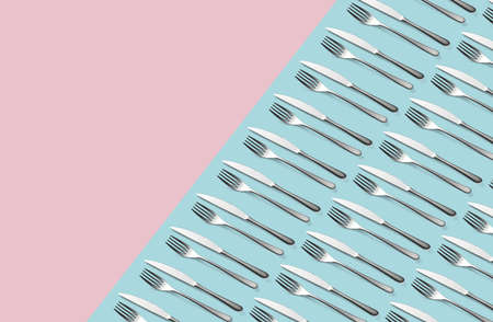 Knife and fork flat lay pattern on pastel pink and blue background. Many metallic forks, and knives top view concept Background for menu Restaurant backdrop. Creative top view pattern Copy free space.の写真素材