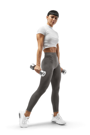 Young athletic girl with dumbbells in her hands. Athletic fit and muscle female body on white background. Bodybuilder in sportswear. Concept of healthy life and sports nutrition.の写真素材