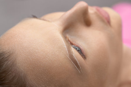 Eyebrow permanent make-up. Woman Having Permanent Make-up Tattoo on her Eyebrows. Closeup beautician doing tattooing eyebrow. Professional makeup and cosmetology skin care.の写真素材
