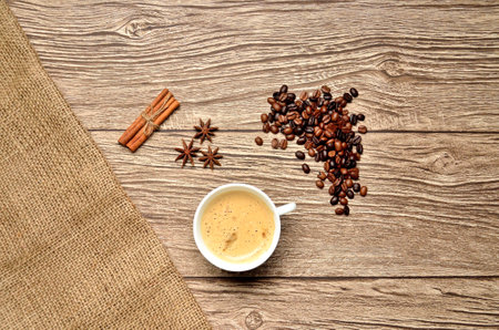 A presentation of hot coffee in white cup with mix coffee beans, anise stars and cinnamon sticksの写真素材