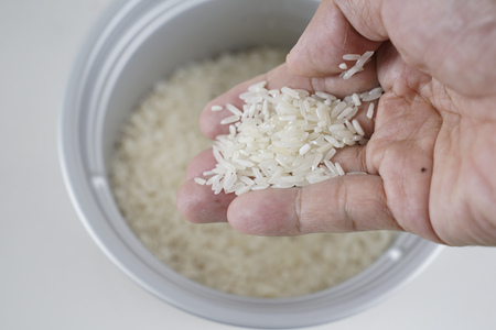 hand scooping uncooked riceの写真素材