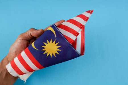 Malaysia flag origami paper plane in hand on blue backgroundの写真素材