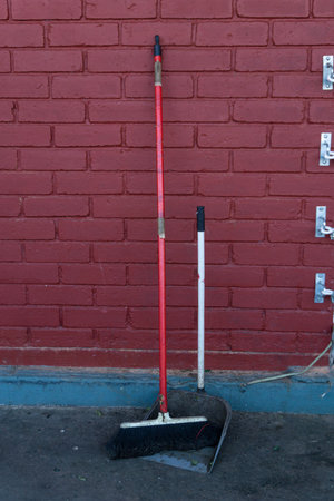 A red and white mop stands on the street near a red brick wall.の写真素材