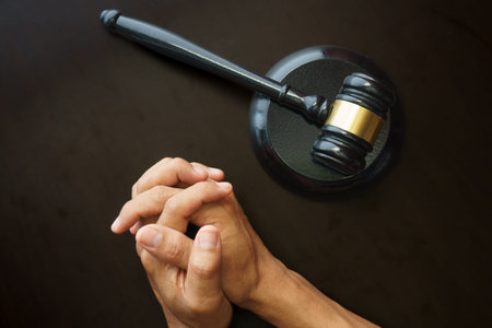 Close up of judge's gavel and hand on black background.