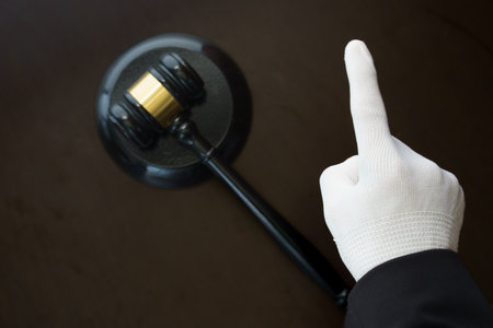 judge's hand with white glove and gavel on dark backgroundの写真素材