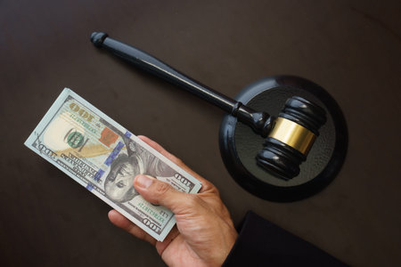 judge's hand with money and gavel on the brown background