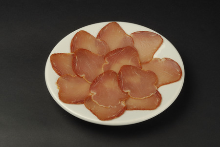 plate of pork loin cured on black backgroundの写真素材