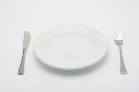 Empty plate, fork and knife on white backgroundの写真素材