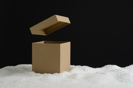 Gift box with lid lifted in the snow on black backgroundの写真素材