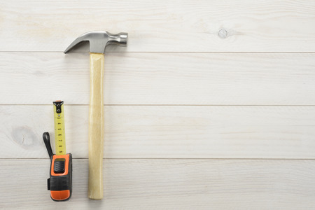Hammer and tape measure on white wooden background, tools for workの写真素材