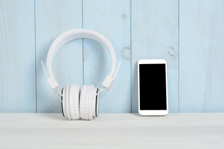 Headset and telephone on white wooden table and blue wallの写真素材