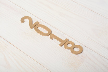 New year two thousand and eighteen in golden wood letters on wooden background, 2018
